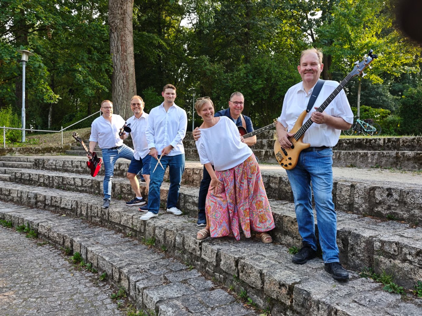 Die sieben Mitglieder von Lower Market mit Instrumenten auf den Stufen im Park